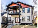 Two-story home with eye-catching red and black accents, a second story balcony, and covered entry porch at 1015 Churchman Ave, Indianapolis, IN 46203