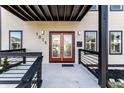 Charming covered front porch featuring a red double door with decorative glass panels and black railing at 1015 Churchman Ave, Indianapolis, IN 46203