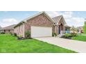 Charming brick home featuring a two-car garage, manicured lawn, and welcoming curb appeal at 5707 Kensington Blvd, Plainfield, IN 46168
