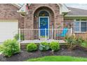 Inviting front porch adorned with a blue door, decorative wreath, and charming landscaping at 5707 Kensington Blvd, Plainfield, IN 46168