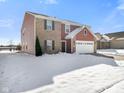 Two-story home with brick and red siding, white garage door, and snowy front yard at 2687 Wildflower Ln, Greenwood, IN 46143