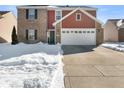 Two-story brick and red-sided home with a white garage door and snow-covered yard at 2687 Wildflower Ln, Greenwood, IN 46143