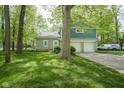Charming two-story home with a combination of stone and blue siding, complemented by a well-manicured lawn and mature trees at 1127 Grant Cir, Cicero, IN 46034