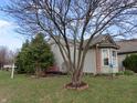 Well-maintained home exterior featuring a For Sale sign, lush greenery, and a cozy red bench at 744 Helm Dr, Avon, IN 46123
