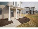 Inviting front porch with white columns, gray brick facade and well-manicured flower beds at 7904 Magnolia St, New Palestine, IN 46163