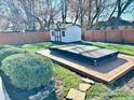 Landscaped backyard featuring a hot tub on a wood deck, decorative shed, and a wood privacy fence at 562 Nelson Dr, Brownsburg, IN 46112