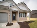 Inviting entryway to a single-Gathering home featuring a covered porch, a dark front door and manicured landscaping at 6322 Granby Dr, Whitestown, IN 46075