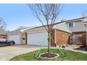 Two car garage with a concrete driveway, and a newly planted tree in the front yard at 5527 Vin Rose Ln, Lawrence, IN 46226