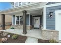 Inviting front porch with stone accents, dark wood pillars, and a stylish front door at 19955 Boulder Brook Ln, Westfield, IN 46074