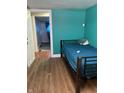 Bedroom featuring blue walls, wood-look floors, and a simple metal bed frame at 4524 E 10Th St, Indianapolis, IN 46201