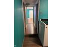 Hallway with teal walls, white doors, and wood-look floors leading to the entrance door at 4524 E 10Th St, Indianapolis, IN 46201