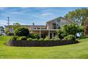 Lush backyard with a stone retaining wall, mature trees, and a balcony with large windows at 9454 Raintree S Dr, Columbus, IN 47201
