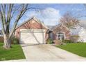 Charming brick single-story home with attached two-car garage, beautiful lawn, and mature tree at 10656 Adam Ct, Fishers, IN 46037