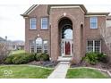 Stately brick home with arched entryway, manicured shrubs and walkway at 11704 Gray Eagle Dr, Fishers, IN 46037