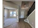 Inviting foyer with hardwood floors, stairs with black railings, and a spacious living room with large windows at 1019 Cyprian Way, Lebanon, IN 46052