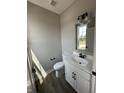 A half bathroom with a white vanity, black hardware, and wood look flooring at 12023 Crestwater Ct, Fishers, IN 46037