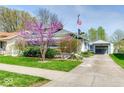 Quaint home featuring mature flowering trees, detached garage, and manicured lawn at 1641 Winton Ave, Indianapolis, IN 46224