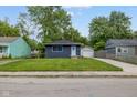 Charming single-story home featuring a well-maintained lawn, blue door, and convenient detached garage at 3125 N Tacoma Ave, Indianapolis, IN 46218