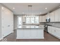 Bright kitchen featuring white cabinets, stainless steel appliances, a large island, and wood-look flooring at 7340 W County Road 600 Rd, McCordsville, IN 46055