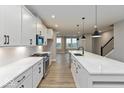 Modern kitchen features white cabinets, stainless steel appliances, an island with a sink, and hardwood floors at 7344 W County Road 600, McCordsville, IN 46055