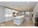 Bright kitchen boasts a large island, sleek pendant lighting, white cabinets, modern appliances, and wood flooring at 7344 W County Road 600, McCordsville, IN 46055