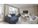 Cozy living room features a plush blue sectional, large windows, neutral tones, and stylish decor at 7348 W County Road 600 Rd # 12-604, McCordsville, IN 46055