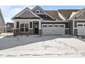 Charming home with stone accents, a two-car garage, and a covered entrance amidst a snowy landscape at 3509 Wrangler Dr, Bargersville, IN 46106