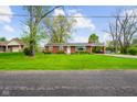 A single-story red brick home with an attached carport and a spacious green lawn at 56 Hadley Woodland St, Mooresville, IN 46158