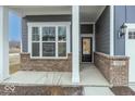 Welcoming covered entryway with brick accents and a modern black front door at 3922 Holly Brook Dr, Westfield, IN 46062