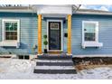 Charming blue house featuring a welcoming front door with stylish wooden pillar accents and snowy front yard at 4360 Guilford Ave, Indianapolis, IN 46205
