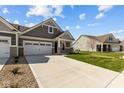 Lovely gray home with a two-car garage, long driveway and well-kept lawn on a sunny day at 16689 Cattle Hollow Ln, Noblesville, IN 46060