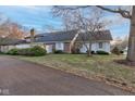 Single-story home featuring a brick facade, white trim, mature trees, and a manicured lawn at 2856 Jamieson Ln, Indianapolis, IN 46268