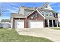 Front exterior featuring a brick facade with three-car garage and wide driveway on a sunny day at 5128 Macaferty St, Plainfield, IN 46168