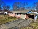 Single-story brick home with a driveway, garage, and covered area perfect for outdoor storage at 11962 Trolley Rd, Indianapolis, IN 46236