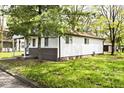 Exterior view of a single-story home with a covered porch and green lawn surrounded by trees at 715 N Warman Ave, Indianapolis, IN 46222