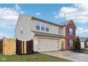 Two-story home with beige siding, a two-car garage, and a wooden fence at 7988 Kersey Dr, Indianapolis, IN 46236