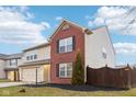 Two-story home with red brick and beige vinyl siding, a two-car garage, and a fenced yard at 7988 Kersey Dr, Indianapolis, IN 46236