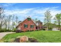 Expansive lush lawn surrounds this two-story brick home, accented by mature trees and meticulous landscaping at 1398 Penny Ln, Greenfield, IN 46140