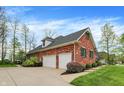 Side view of the home features a two-car garage and lush landscaping, offering privacy at 1398 Penny Ln, Greenfield, IN 46140