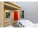 Red front door entrance with snow covered landscaping at 3740 Magenta Ln # 5, Indianapolis, IN 46214
