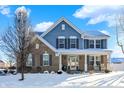 Two-story house with blue siding, brick accents, and a covered porch; snow on the ground at 1401 W Springhurst Blvd, Greenfield, IN 46140