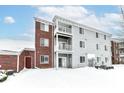 Rear view of condo building with snow and AC units at 6239 Amber Creek Ln # 104, Indianapolis, IN 46237