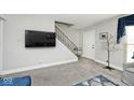 Living room with gray walls, flat screen TV, and stairs leading upstairs at 8021 E 20Th St, Indianapolis, IN 46219