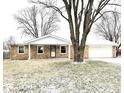 Ranch home with a snow-covered lawn and mature trees in front at 2006 E 44Th St, Anderson, IN 46013