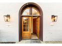 Arched entryway with glass paneled doors, classic sconces, and a welcome mat for guests at 304 N College Ave # Apt B, Indianapolis, IN 46202