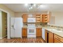 Galley kitchen with wood cabinets, white appliances, and mosaic backsplash at 2716 Redland Ln, Indianapolis, IN 46217