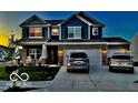 Two-story home with gray and blue siding, three-car garage, and landscaped lawn at dusk at 507 Buckthorn Ln, Sheridan, IN 46069