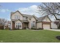 Two-story house with brick and siding, attached garage, and grassy yard at 6023 Twyckenham Dr, Indianapolis, IN 46236