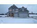 Two-story home with a two-car garage, gray siding, and a covered front porch during the winter season at 1123 Ridgevine Rd, Greenwood, IN 46143