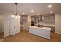 Bright open kitchen with a center island, gray cabinets, stainless steel appliances, and light wood flooring at 1123 Ridgevine Rd, Greenwood, IN 46143